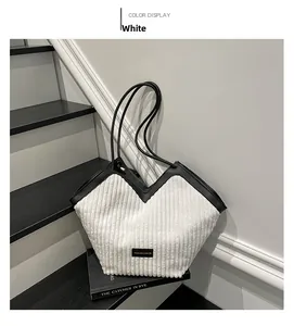 Detail of white striped tote bag with black leather trim and Fashion logo on a book