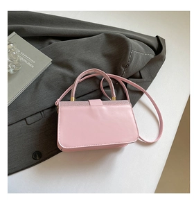 Gros plan du sac bandoulière en cuir rose avec bordure à paillettes sur un blazer chic