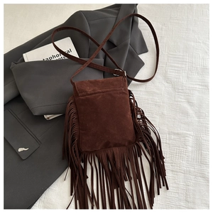 Détail d'un sac à bandoulière en daim marron foncé avec longues franges bohèmes