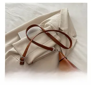 Detail of caramel PU leather crescent bag with adjustable strap and silver buckle