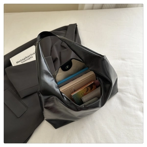 Vista interna della borsa tote in pelle lucida nera con grande capacità per libri e portafoglio