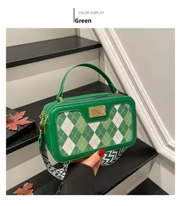 Detail of green leather handbag with argyle pattern and wide chevron canvas strap