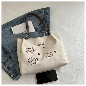 Detailed flat lay of canvas tote bag featuring cute cat illustrations and leather handles
