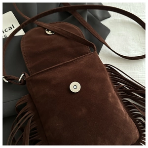 Détail macro du sac bandoulière en daim marron foncé avec de longues franges bohèmes