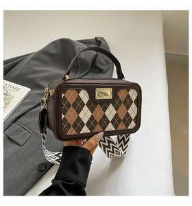 Detail of vintage checkered square bag with geometric strap and gold plaque accent