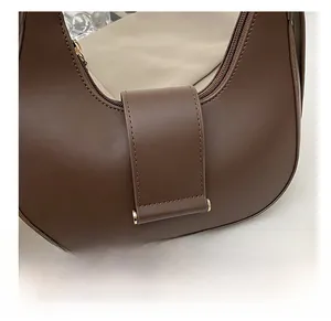 Close-up of smooth dark brown leather texture and golden metal hardware on shoulder bag