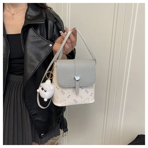 Detail view of mini crossbody bag with silver heart buckle and plush ball charm