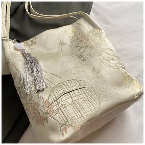 Detailed view of floral jacquard fabric and tassel pendant on Chinese bucket bag