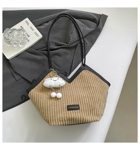 Detail of khaki corduroy tote bag with black leather straps and white cloud pendant