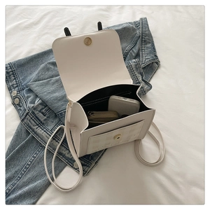 Detail view of cream leather backpack open to show internal storage and plaid front pocket