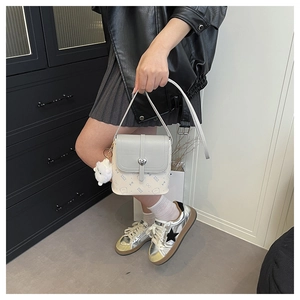 Detail of grey crossbody bag with heart lock and fluffy charm on student style outfit
