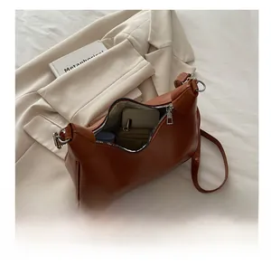 Brown faux leather crescent bag with zipper open showing inner capacity and wallet