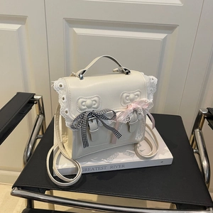 Borsa in PU color crema con bordi in pizzo e fiocchi decorativi su un libro bianco