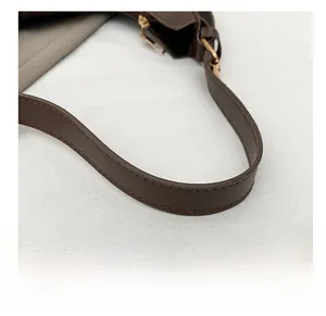Close-up of dark brown leather handbag strap with neat stitching and gold hardware