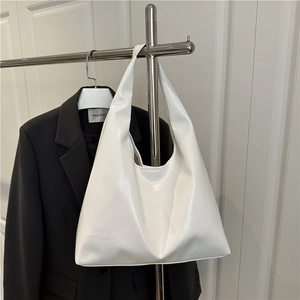 Borsa tote minimalista in pelle bianca lucida appesa a un appendiabiti in acciaio