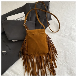 Détail d'un sac bandoulière en daim marron avec de longues franges bohèmes et boucles argentées