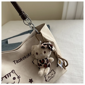 Detail of beige canvas tote with Hello Kitty plush charm and metal chain strap