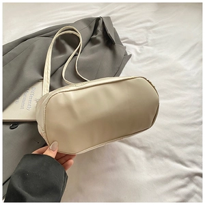 Detail view of the wide oval base and smooth synthetic leather texture of the beige bucket bag