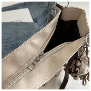 Detail of canvas tote bag with silver zipper closure and plush leopard bow charm