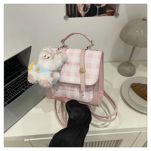 Detail of pink checkerboard backpack with cartoon bear print and plush dog charm