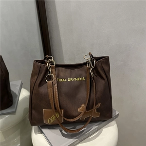 Sac cabas en toile marron avec texte 'TIDAL DRYNESS' et patch chien sur un tabouret