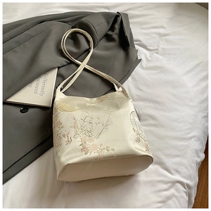 Detail of off-white satin bucket bag featuring traditional Chinese embroidery and bamboo motifs