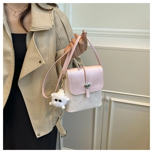 Detail of pink bucket bag featuring a heart buckle and cute plush monster pendant
