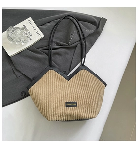 Close-up of khaki corduroy tote bag with black leather straps and fashion label detail