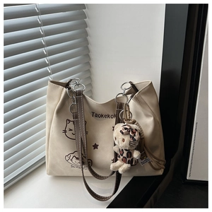 Close-up of canvas tote bag featuring cute cat print and plush cat pendant accessory
