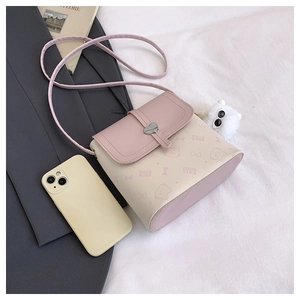 Detail of pink and beige crossbody bag with heart clasp and fuzzy pompom charm