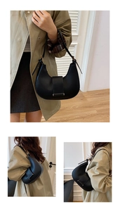 Detail view of a black crescent underarm bag with decorative strap and matte finish