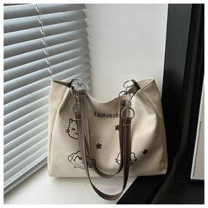 Detail of cream canvas tote bag with brown straps and cute cartoon cat illustration