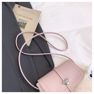 Detail of pink and white crossbody bag featuring a silver heart buckle and bow print