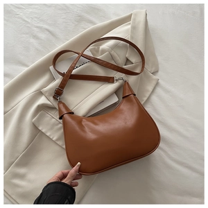 Detail view of the brown crescent bag showing the smooth faux leather texture and strap