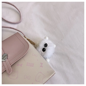 Detail of pink and white crossbody bag featuring heart clasp and cute cat pattern