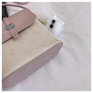 Close-up of pink cat prints and heart-shaped metal buckle on a stylish crossbody bag