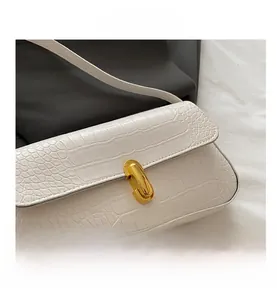 Détail du sac à bandoulière en similicuir croco blanc avec fermoir capsule doré