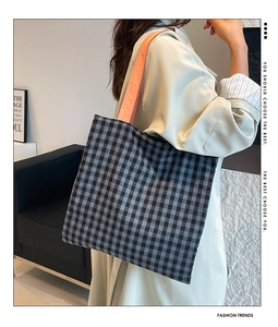 Detail of checkered tote bag featuring bold orange straps for a modern contrast look