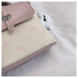 Close-up of pink heart metal clasp and cartoon cat print on faux leather handbag
