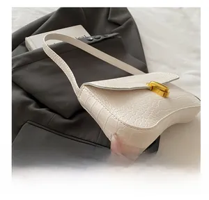 Détail du sac sous le bras blanc à texture crocodile et fermoir rotatif en métal doré