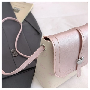 Detail of mini crossbody bag showing silver heart metal clasp and pink cartoon cat print