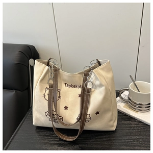 Close-up of beige canvas tote bag with leather handles and cartoon cat illustration