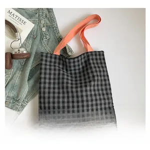 Détail du sac cabas à carreaux avec anses orange, stylisé avec une veste en jean