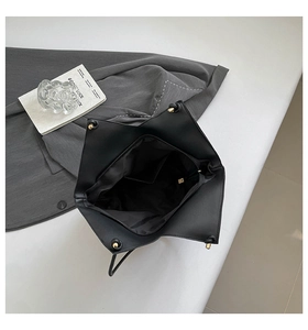 Top view of spacious black tote bag with gold metal accents and inner pocket detail