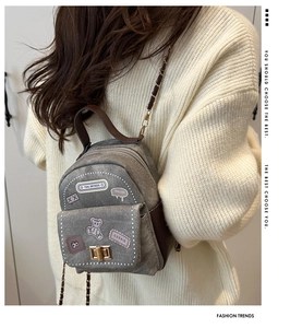 Detail view of denim mini backpack with cartoon patches and leather chain straps