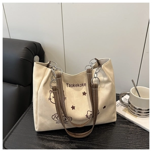 Detailed view of cream canvas tote featuring brown cat print and faux leather straps