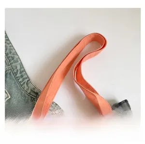 Détail des sangles orange et du tissu en toile à carreaux noir et gris du sac