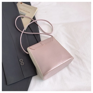 Detail of a pink and beige color-block crossbody bag on a grey blazer background