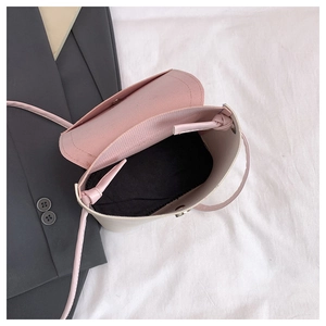 Detail view of pink flap crossbody bag with creamy white body and black inner lining