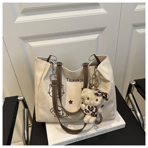 Detail of canvas tote bag with brown leather straps and cute cartoon cat illustration